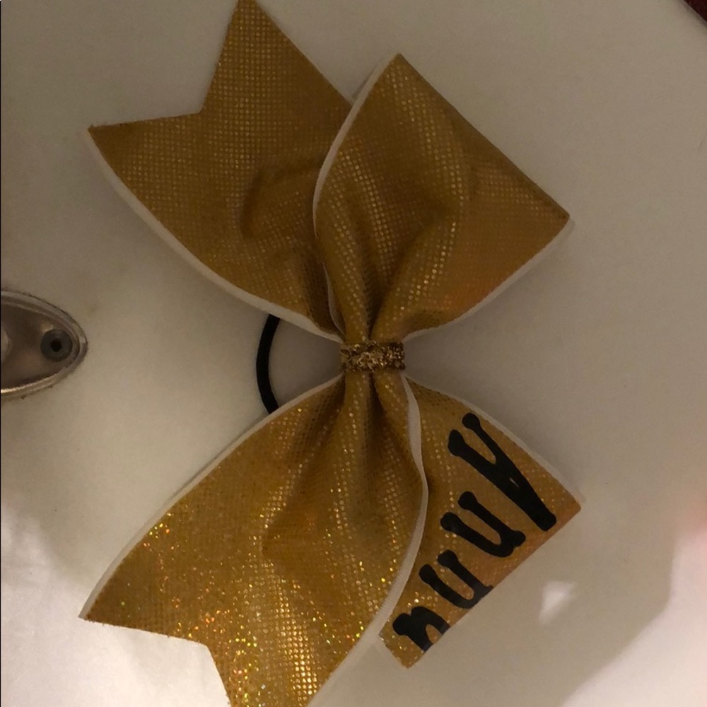 Gold cheer bow that says Anna